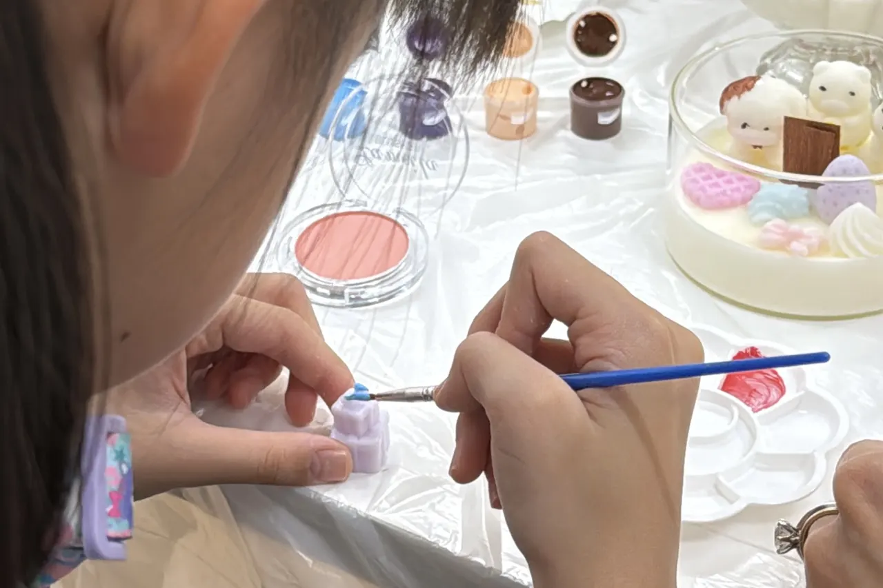 Painting and decorating a candle at a White Pixies studio session in Singapore, a hands-on twist on art jamming