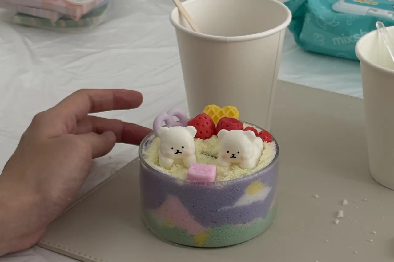 A pastel sand art candle topped with two little wax bears, made at a White Pixies workshop in Singapore